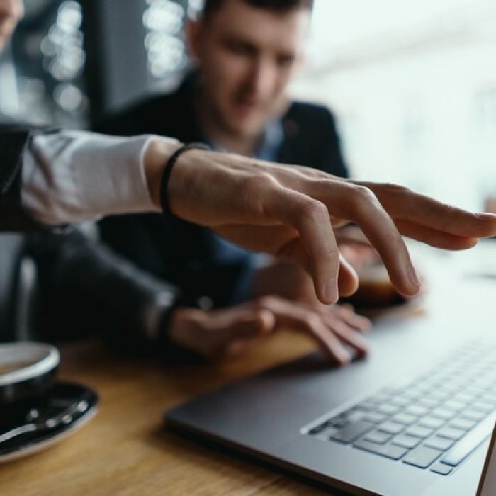 two-businessmen-pointing-laptop-screen-while-discussing_158595-5326